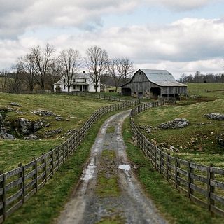A gray limestone ledge rising through a green spring pasture with a wire fence along the top